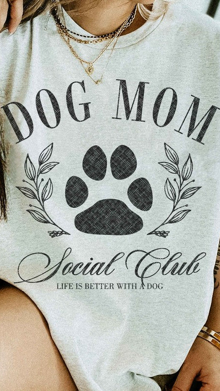 Ash colored Graphic short-sleeved T-shirt on a model that reads "Dog Mom Socal Club".