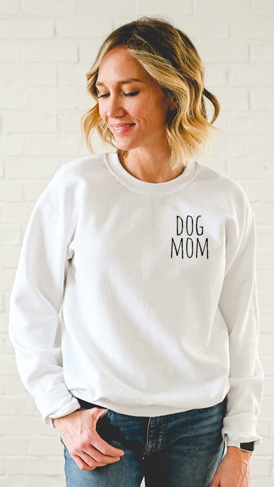Dog Mom text on the left chest of a White Sweatshirt on a female model. Shop The House of Blondie