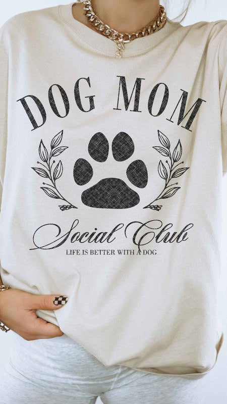 Sand colored Graphic short-sleeved T-shirt on a model that reads "Dog Mom Socal Club".