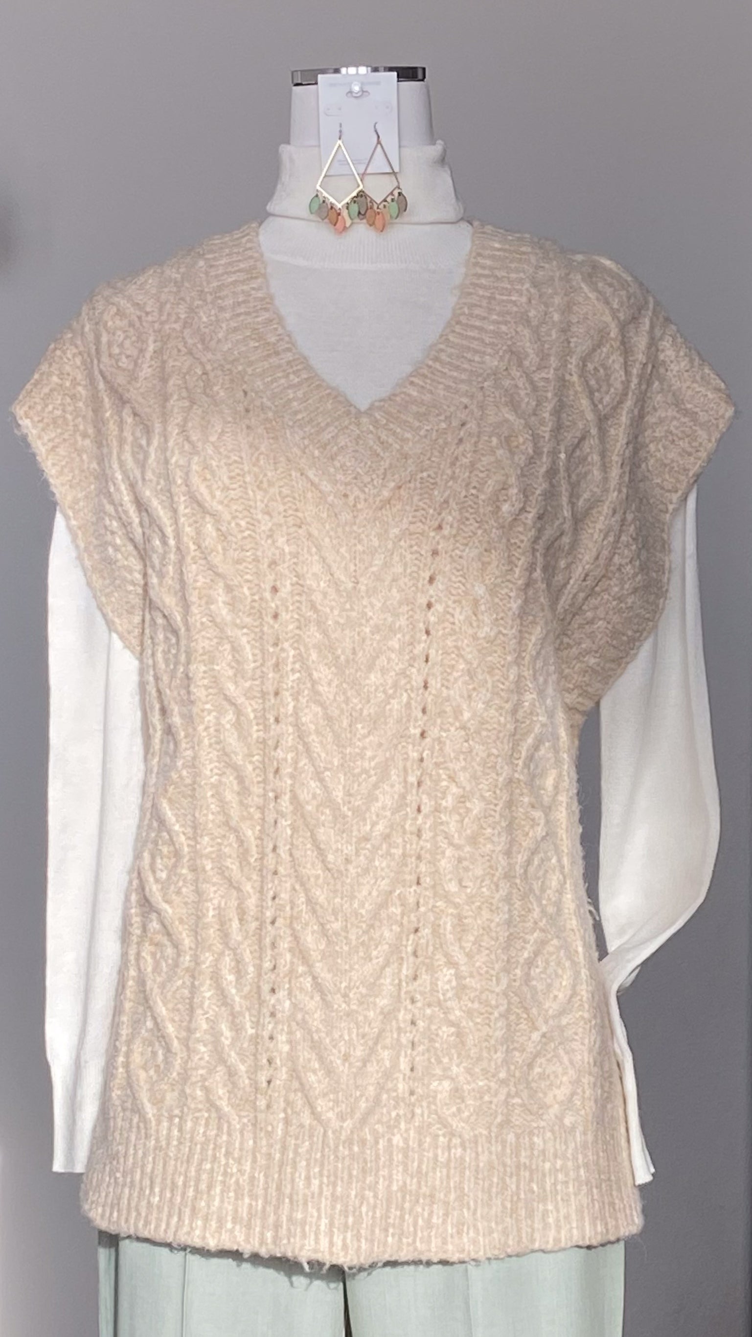 Beige V-neck cable knit sweater vest on a mannequin. Shop at www.thehouseofblondie.com