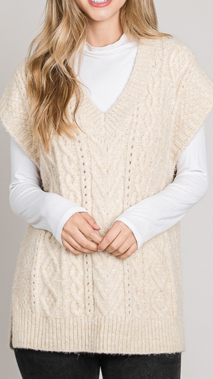 Model wearing the beige Quinn Cable-Knit v-neck sweater vest over a white long-sleeve shirt.