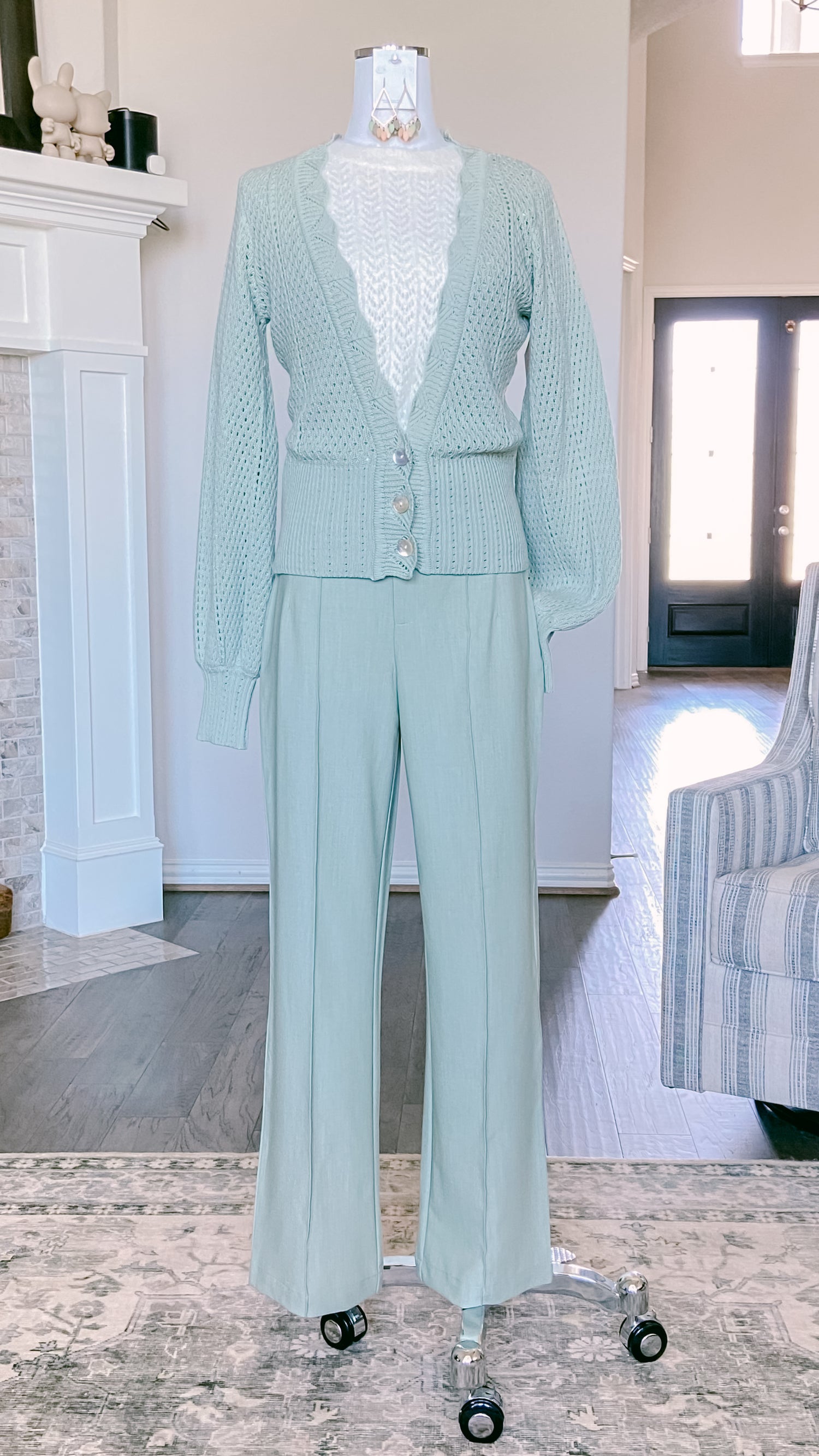 Sage Cardigan and pants on a mannequin in a room with a fireplace and striped chair